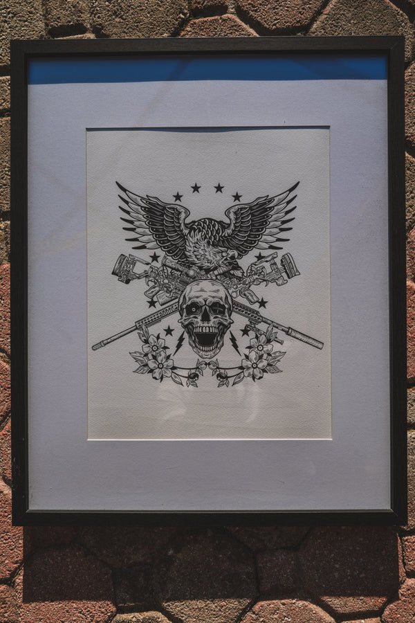 Framed black and white illustration of an eagle with a skull on a textured surface